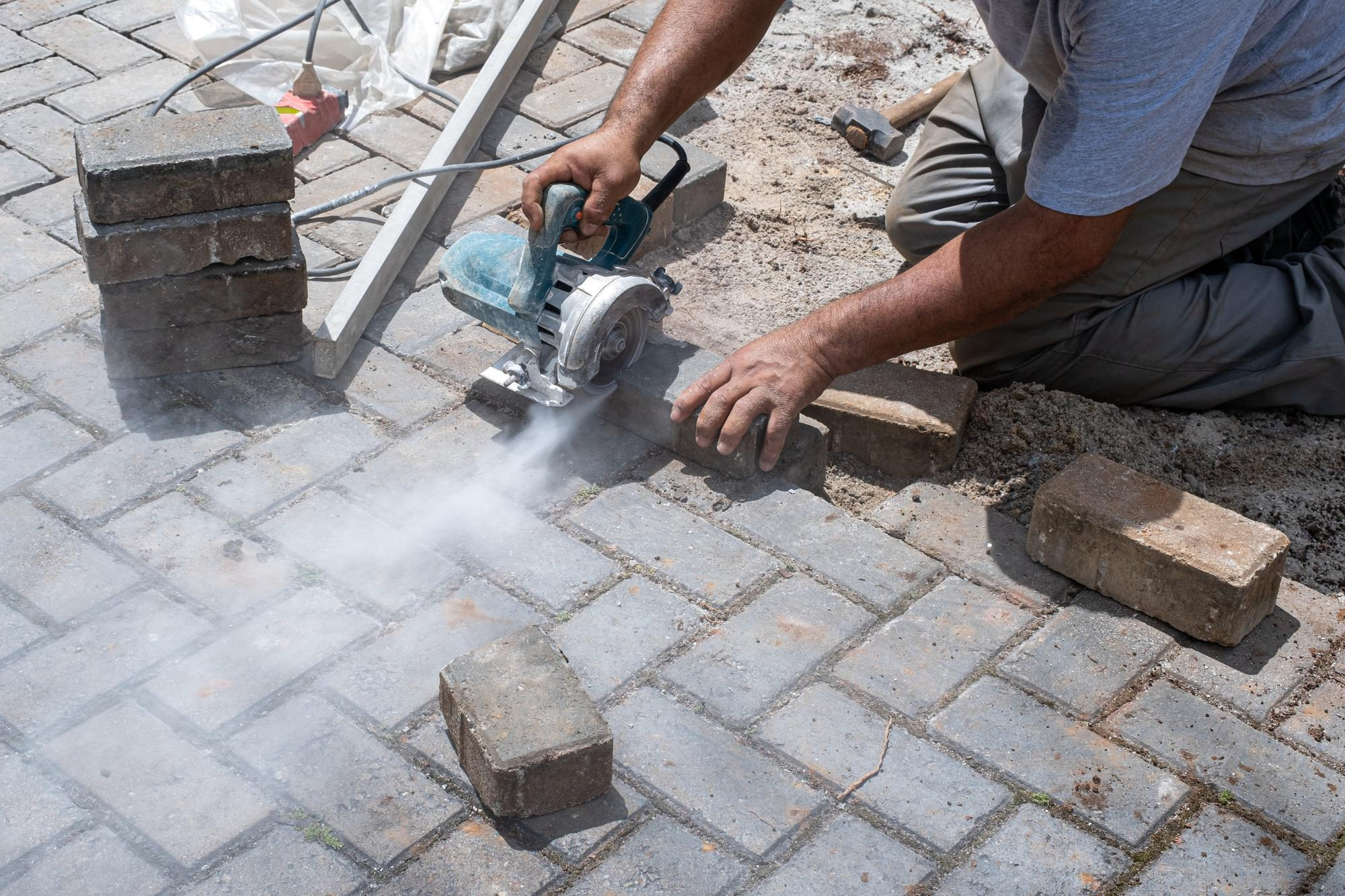 Hardscape contractor cutting pavers for patio installation – Concrete Pro Dallas