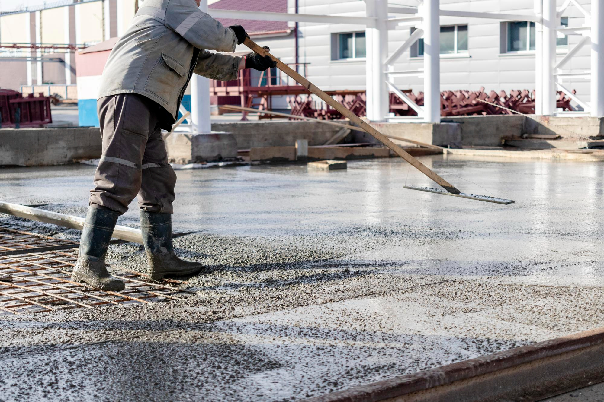 Crew leveling wet concrete slab with screed tool on construction site – Concrete Pro Dallas