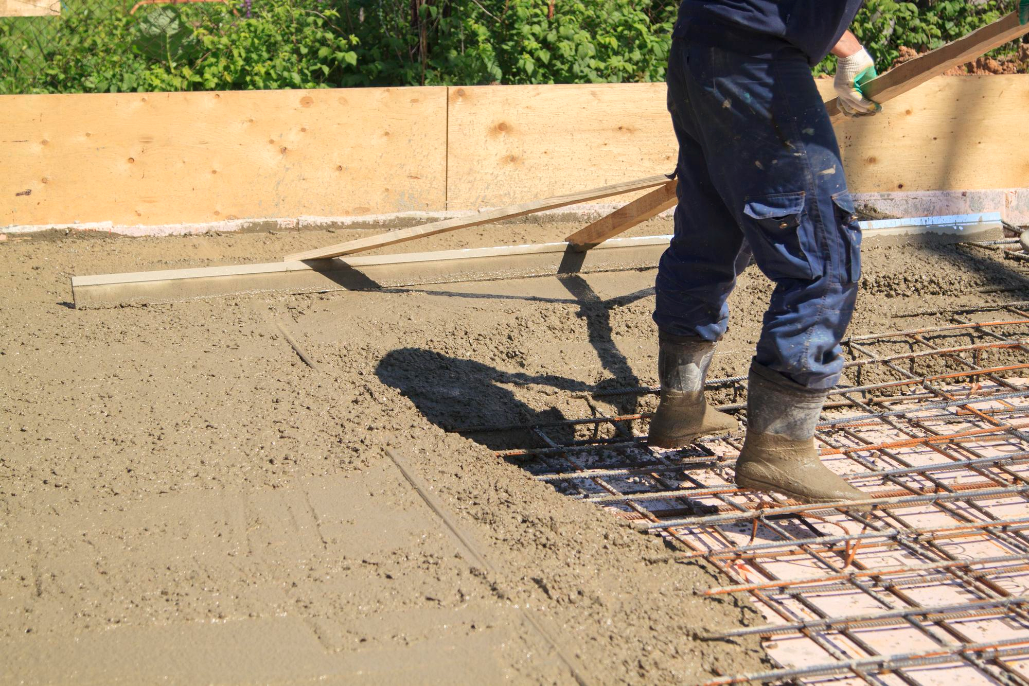 Worker leveling wet concrete over rebar reinforcement – Concrete Pro Dallas